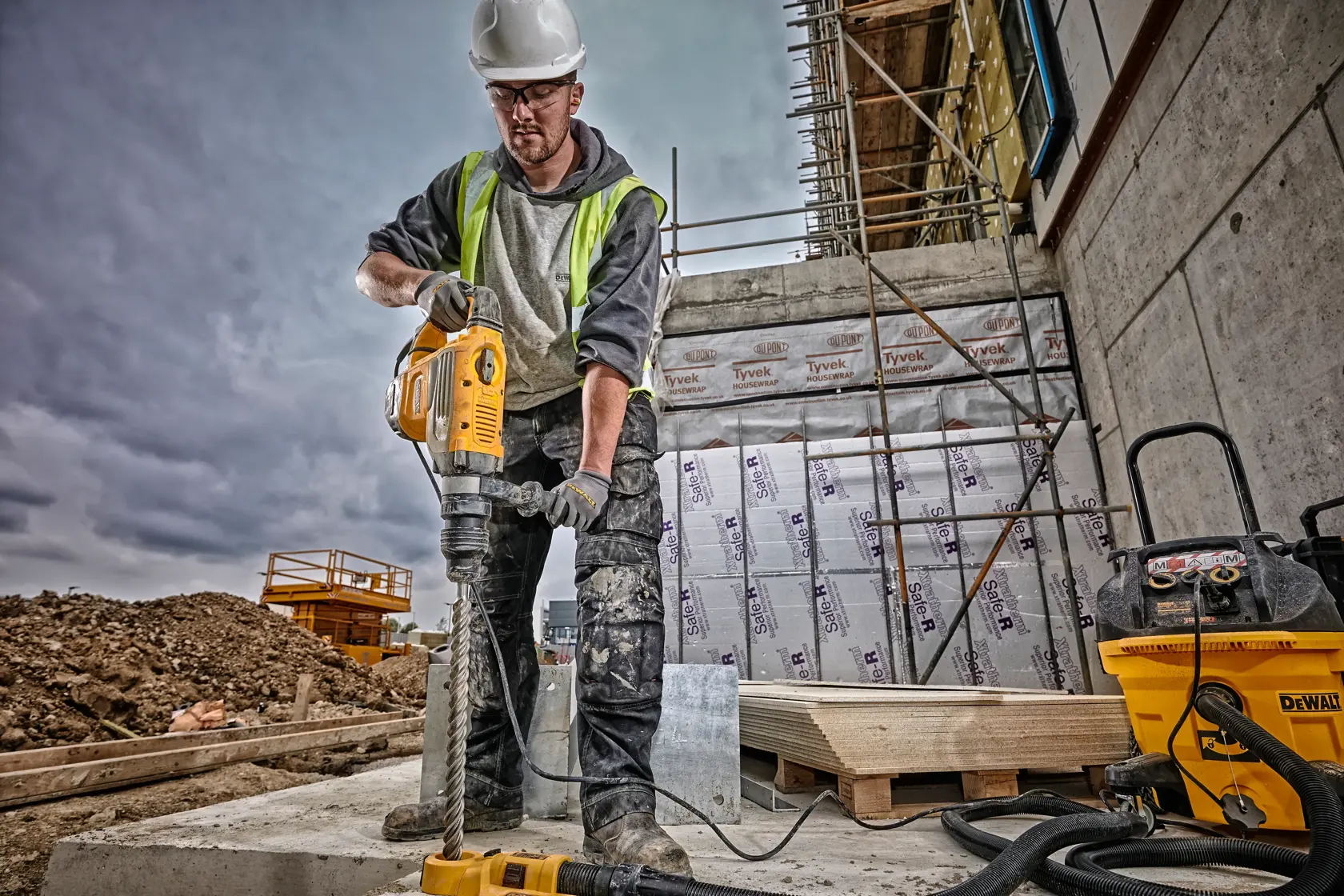 A DeWALT electric rotary hammer drill with a yellow and black body, side handle, and corded power supply.