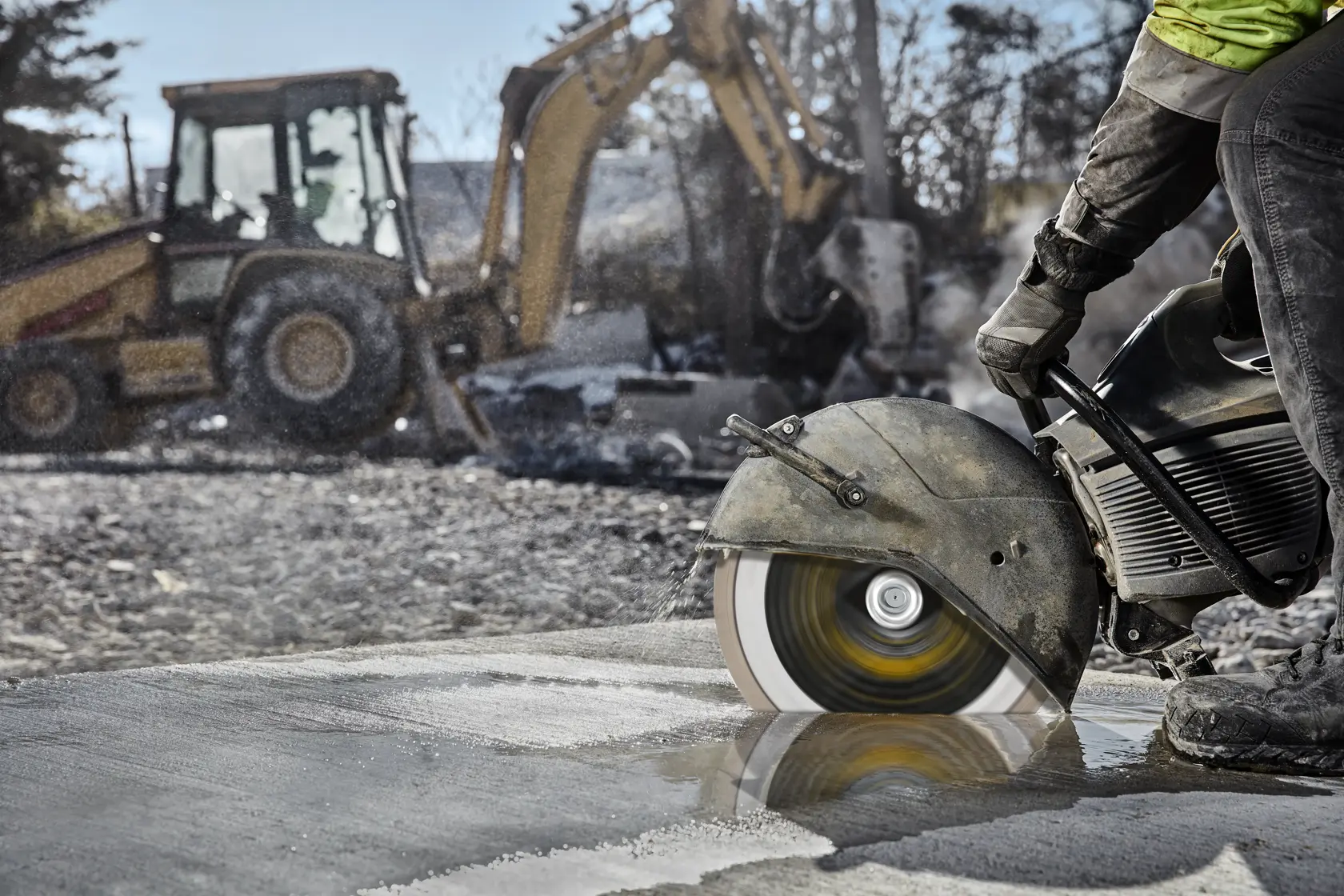 Eine DEWALT-Säge mit DT20462-Blatt schneidet Beton auf Baustelle. Baumaschinen im Hintergrund.