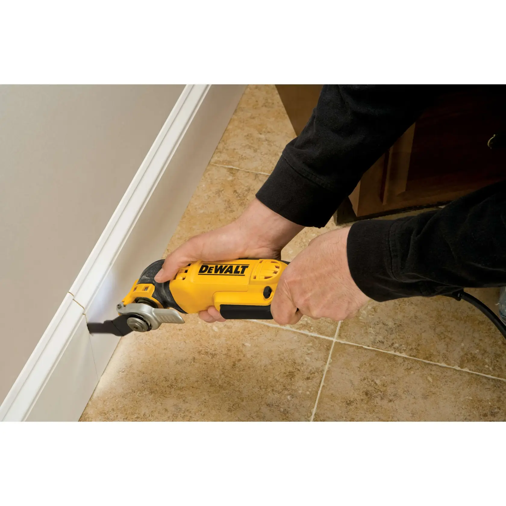 Persona usa herramienta oscilante DEWALT para cortar junto a un zócalo en suelo de baldosas.