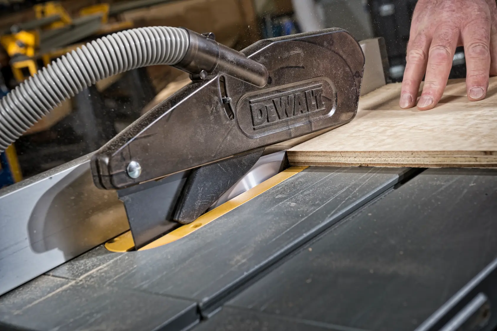 DEWALT Tischsäge schneidet Holz mit Staubabsaugung und Schutzvorrichtung.