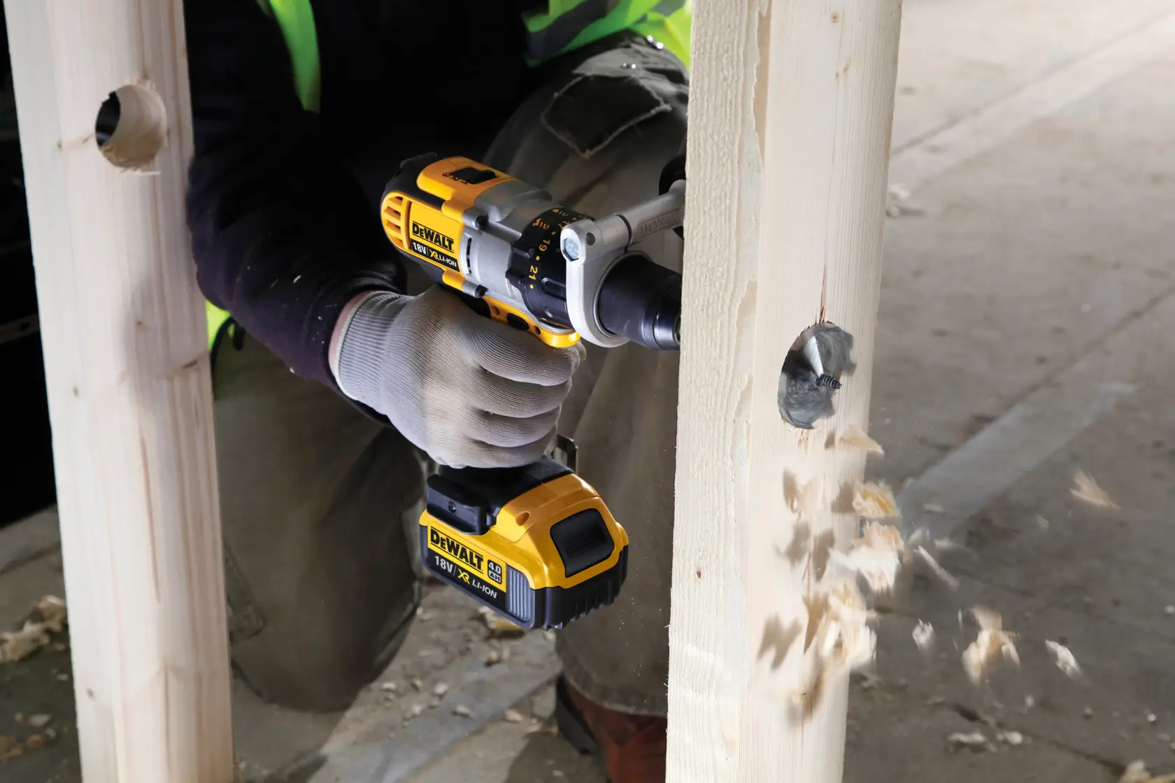 Taladro inalámbrico DEWALT perfora una viga de madera, astillas de madera vuelan.