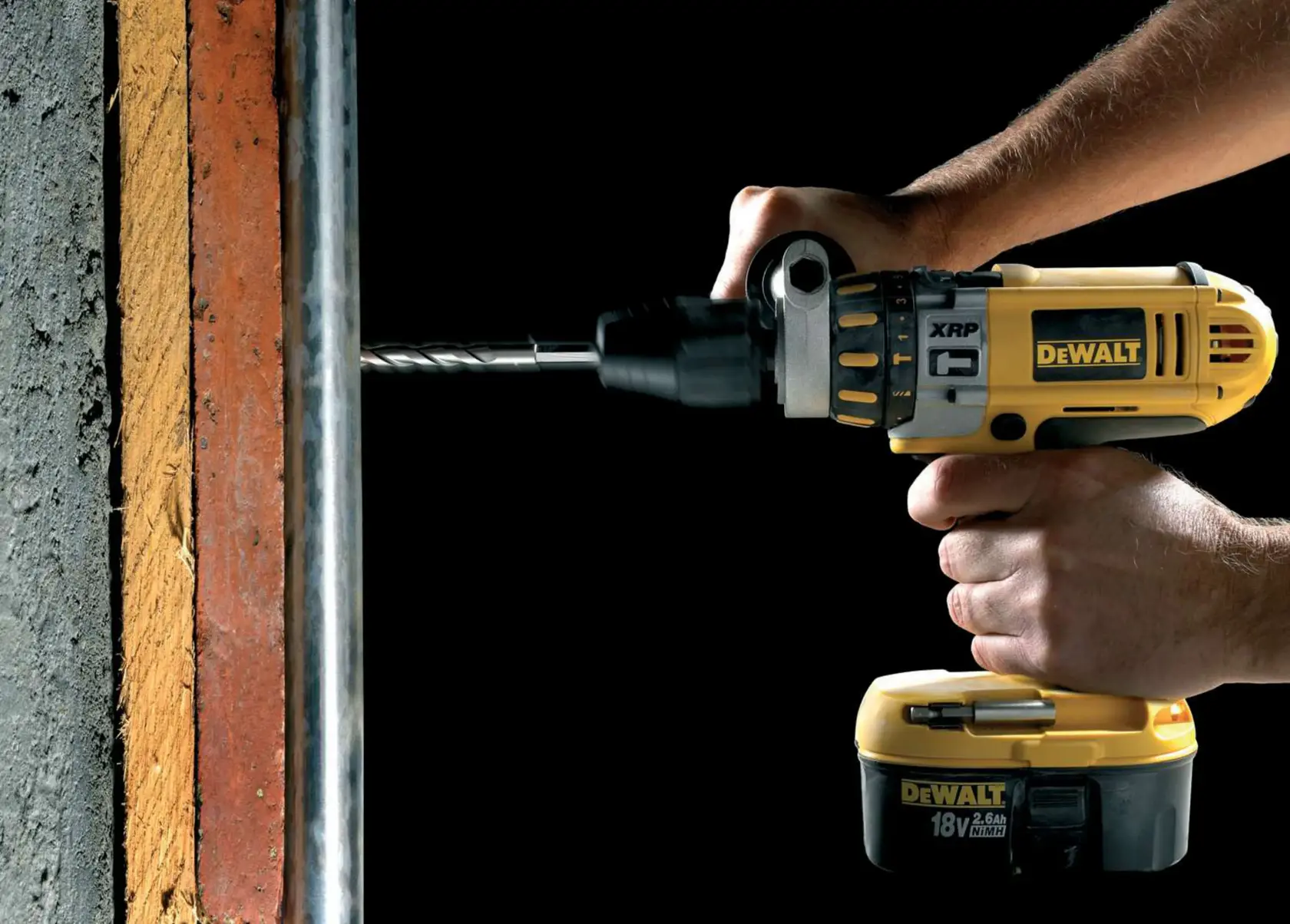 Taladro inalámbrico DEWALT perforando una pared de concreto, sujetado por las manos de una persona.