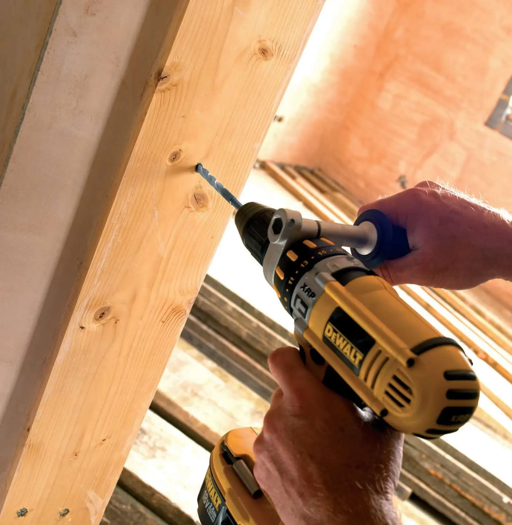 Persona usa un taladro DEWALT para hacer un agujero en una viga de madera en una obra.