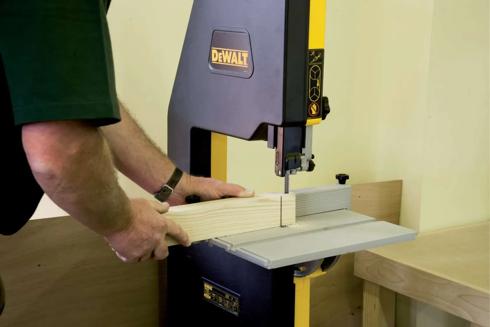 Persona operando sierra de cinta DEWALT para cortar madera en un taller.