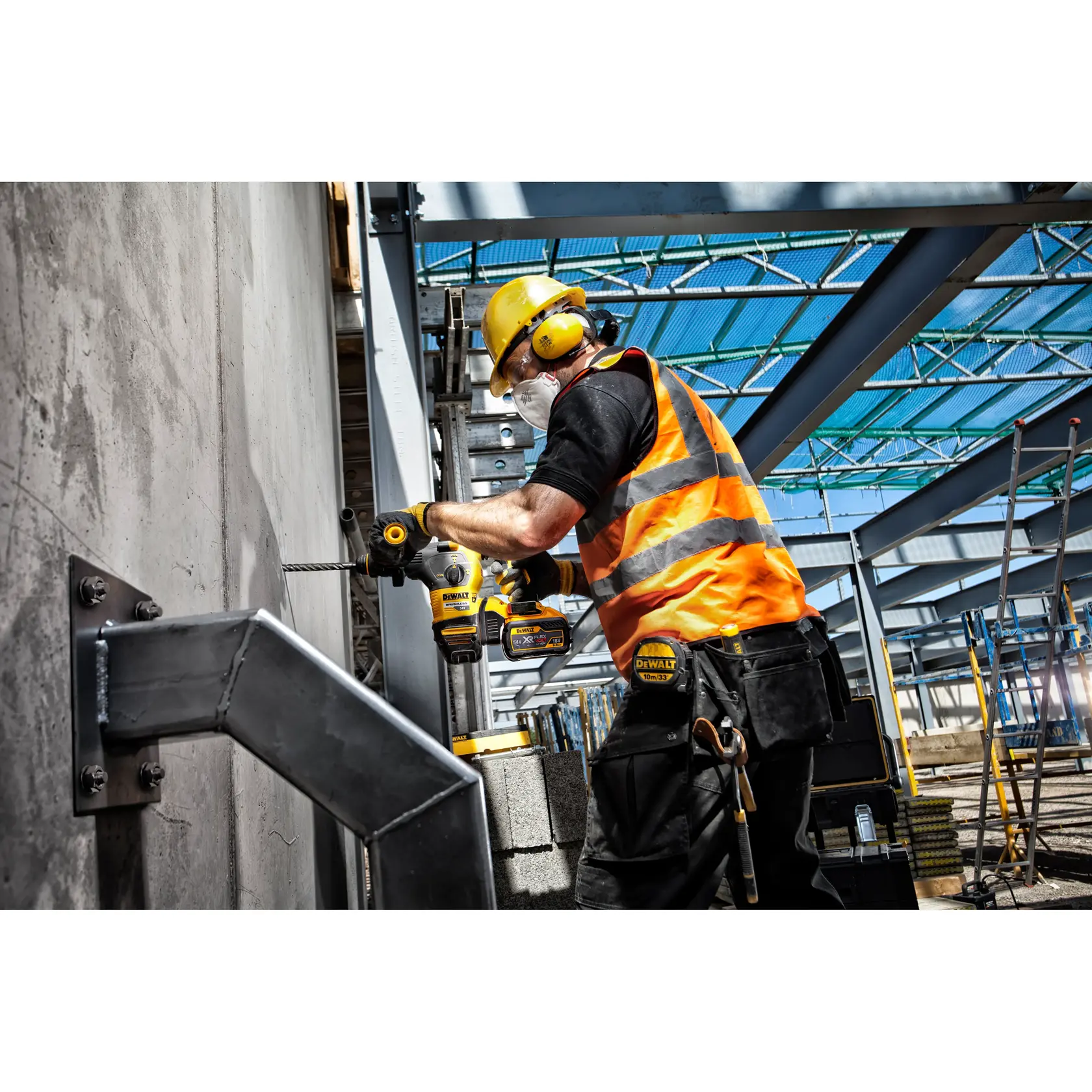 Trabajador perfora pared de concreto en obra con herramienta DEWALT, usa equipo de seguridad y chaleco naranja.