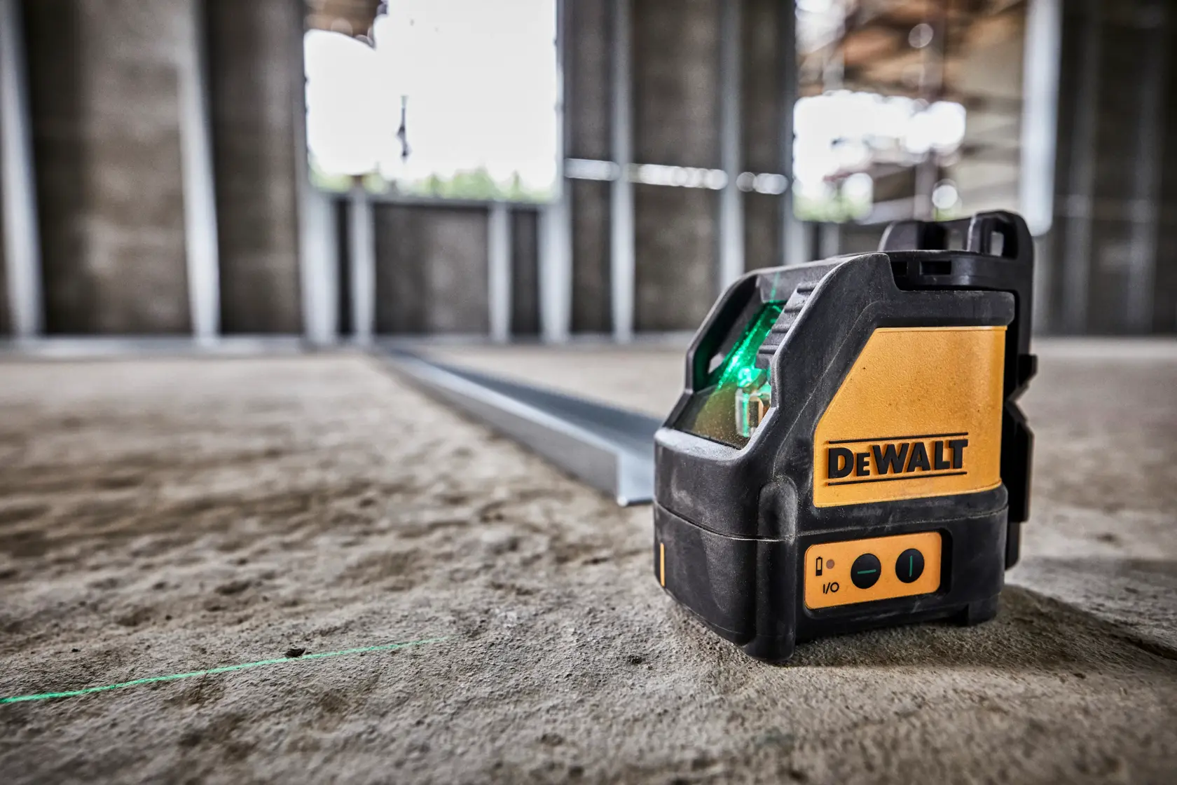 DEWALT grüner Laser DW088CG auf Betonboden Baustelle, projiziert grüne Linie.