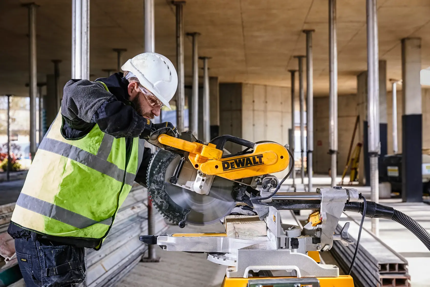 DEWALT DWS780, DWS780KIT Gehrungssäge im Einsatz auf Baustelle. Arbeiter sägt Holz. Kategorie Fotografie.